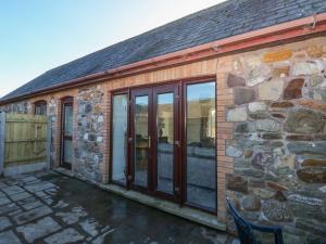 uma casa de pedra com portas de vidro deslizantes em The Old Well Bungalow - Ty Mawr Farm em Cardiff