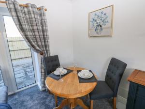 uma sala de jantar com uma mesa de madeira e 2 cadeiras em The Old Well Bungalow - Ty Mawr Farm em Cardiff