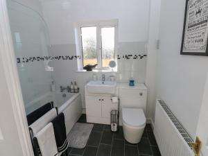 a white bathroom with a tub sink and a toilet at The Old Well Bungalow - Ty Mawr Farm in Cardiff +11 photos