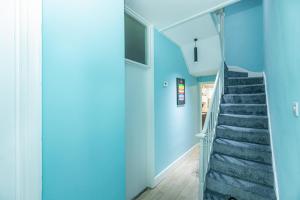 a hallway with blue walls and a staircase at Renovated 3BR wgarden in Stratford, 1min to Train in London