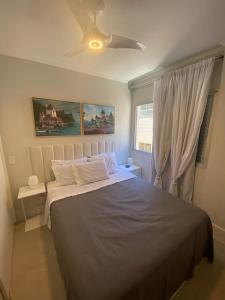 een slaapkamer met een bed en een plafondventilator bij Canto do Forte - AP 106CD in Praia Grande