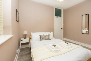 1 dormitorio con 1 cama con toallas en Renovated 3BR wgarden in Stratford, 1min to Train en Londres