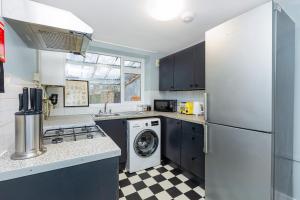 a kitchen with a refrigerator and a washer and dryer at Renovated 3BR wgarden in Stratford, 1min to Train in London
