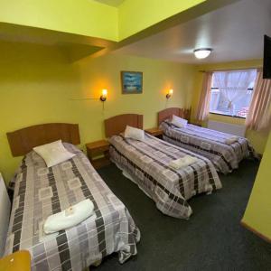 3 camas en una habitación con paredes amarillas en Hotel Yagan Porvenir, en Porvenir