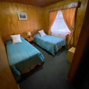 1 dormitorio con 2 camas y ventana en Hotel Yagan Porvenir, en Porvenir