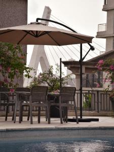 un tavolo e sedie con ombrellone accanto a una piscina di Résidences Les Hauts de l'Indenié a Abidjan