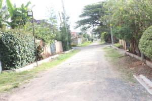 an empty road in a residential neighborhood with trees at Bremu homes near JKIA airport. in Nairobi