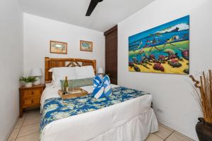 1 dormitorio con 1 cama y una pintura en la pared en Kahana Reef 201, en Kahana