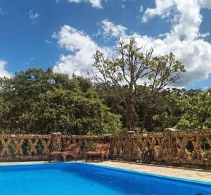 uma piscina com duas cadeiras ao lado de uma parede de pedra em Pousada Meu Recanto em Conceição da Ibitipoca