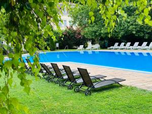 a row of lounge chairs next to a swimming pool at Zala Hills Apartman - Batthyány Villapark in Zalacsány