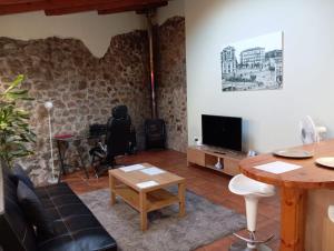 ein Wohnzimmer mit einem Sofa und einem TV in der Unterkunft Apartamentos Las Cuadras de Estaños in Muriedas