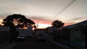 um pôr-do-sol num parque de estacionamento com carros estacionados em Casa no Country em Cascavel