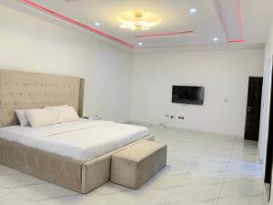 a white bedroom with a bed and a tv at The Residenze Adeniyi Jone Ikeja in Lagos