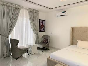 a bedroom with a bed and a chair and a window at The Residenze Adeniyi Jone Ikeja in Lagos
