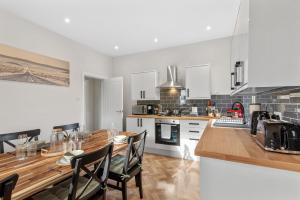 a kitchen with a wooden table and a kitchen with white cabinets at Whitehill House - 3-Bed Home from Home, Sleeps 7, Great for Groups & Workers, FREE Parking & Netflix in Whiston