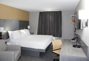 a hotel room with a bed and a chair and a desk at Days Inn by Wyndham Stony Plain in Stony Plain