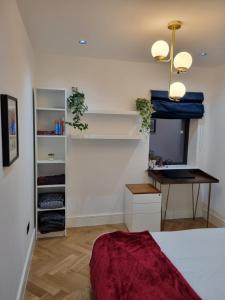 a bedroom with a bed and a desk and a tv at Bright spacious apartment in the park in London