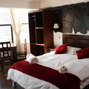 - une chambre dotée d'un grand lit avec des oreillers rouges et blancs dans l'établissement KW HOTEL, à Uyuni