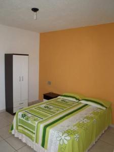 a bedroom with a bed with a green and white blanket at Vila Harmonia in Conde