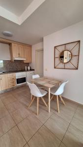 uma cozinha com uma mesa de madeira e cadeiras brancas em Sunny Suite em San Miguel de Abona