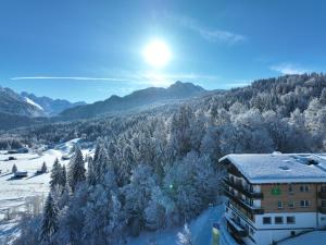 budynek z drzewami pokrytymi śniegiem i górą w obiekcie Naturhotel Café Waldesruhe w mieście Oberstdorf