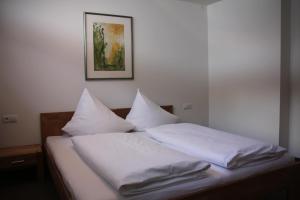 Una cama con sábanas blancas y almohadas. en Familienhotel Mateera Gargellen / Montafon en Gargellen