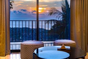 a balcony with a view of the ocean with a table and chairs at The Country Lodge Hotel in Freetown