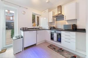 a white kitchen with a sink and a stove at Luxury house close to city center sleeps 6 with free parking in Leicester