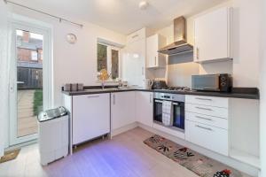 a white kitchen with a sink and a stove at 7Nights Special l Modern House near City Center Sleeps 6 with Free Parking l By Zen Nights Short Lets & Serviced Accommodations in Leicester