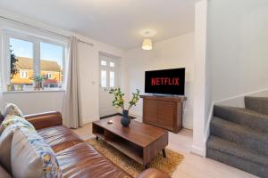 een woonkamer met een bank en een tv bij Luxury house close to city center sleeps 6 with free parking in Leicester