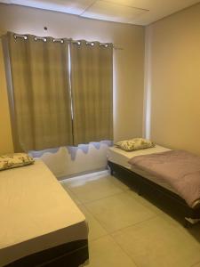 two beds in a room with a window at Linda Casa Próximo Aeroporto in Campo Grande
