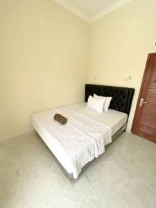 ein weißes Schlafzimmer mit einem Bett mit einem Kissen darauf in der Unterkunft Homestay Kamar Tamu Sitimulyo in Karanggayam