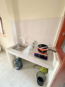 eine kleine Küche mit einem Waschbecken und einem Regal in der Unterkunft Homestay Kamar Tamu Sitimulyo in Karanggayam