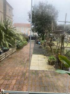- un jardin avec une passerelle en briques en face d'une maison dans l'établissement Rose des sables R d c, à Jullouville
