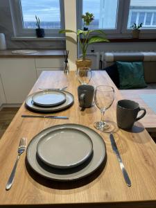 una mesa de madera con platos y utensilios. en Apartament Żwakowska, en Tychy