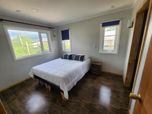 ein Schlafzimmer mit einem Bett und zwei Fenstern in der Unterkunft Casa familiar in Cochrane