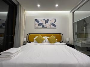una camera da letto con un grande letto bianco con cuscini gialli di Oscar Seaview Apartment a Phu Quoc