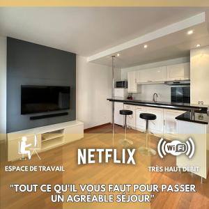 een keuken met witte kasten en een flatscreen-tv bij L'ATHOS - Appartement équipé - Entre Paris et Versailles - Haut débit in Garches