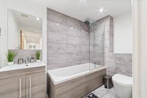 uma casa de banho com uma banheira, um lavatório e um WC. em Modern Apartment with Pool table em Leicester