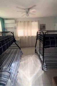 2 Etagenbetten in einem Zimmer mit Deckenventilator in der Unterkunft Villa Retiro R in Boquerón Area in Cabo Rojo