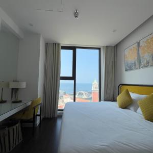 una camera con letto, scrivania e ampia finestra di Oscar Seaview Apartment a Phu Quoc