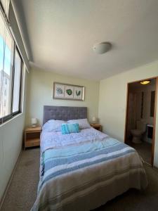 a bedroom with a bed with two blue pillows at Departamento Completo Terrazas San Joaquín La Serena in La Serena