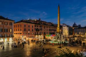 a group of people walking around a city at night at CadensPlace - Overlooking Piazza Navona by dbalconycollection in Rome