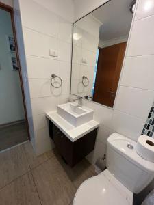 a bathroom with a toilet and a sink and a mirror at Departamento Completo Terrazas San Joaquín La Serena in La Serena