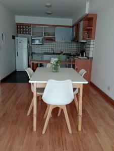 cocina con mesa blanca y sillas blancas en Departamento Ciudad de la Paz en Buenos Aires