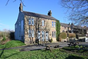 a building with two picnic tables in front of it at Rooms at The Dressers Arms in Chorley