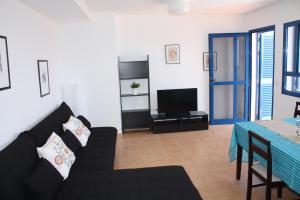 un soggiorno con divano nero e TV di Apartment Orzola Vista Mar a Órzola