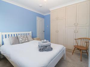 a bedroom with a white bed and a chair at Riverview Apartment in Cemaes Bay