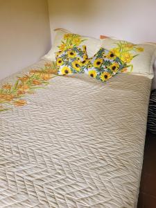 Una cama con almohadas amarillas y azules. en Refúgio Bonanza en Teixeiras