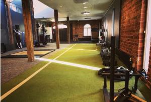 een fitnessruimte met een groene vloer en een bakstenen muur bij Indoor Camping Helsinki in Helsinki